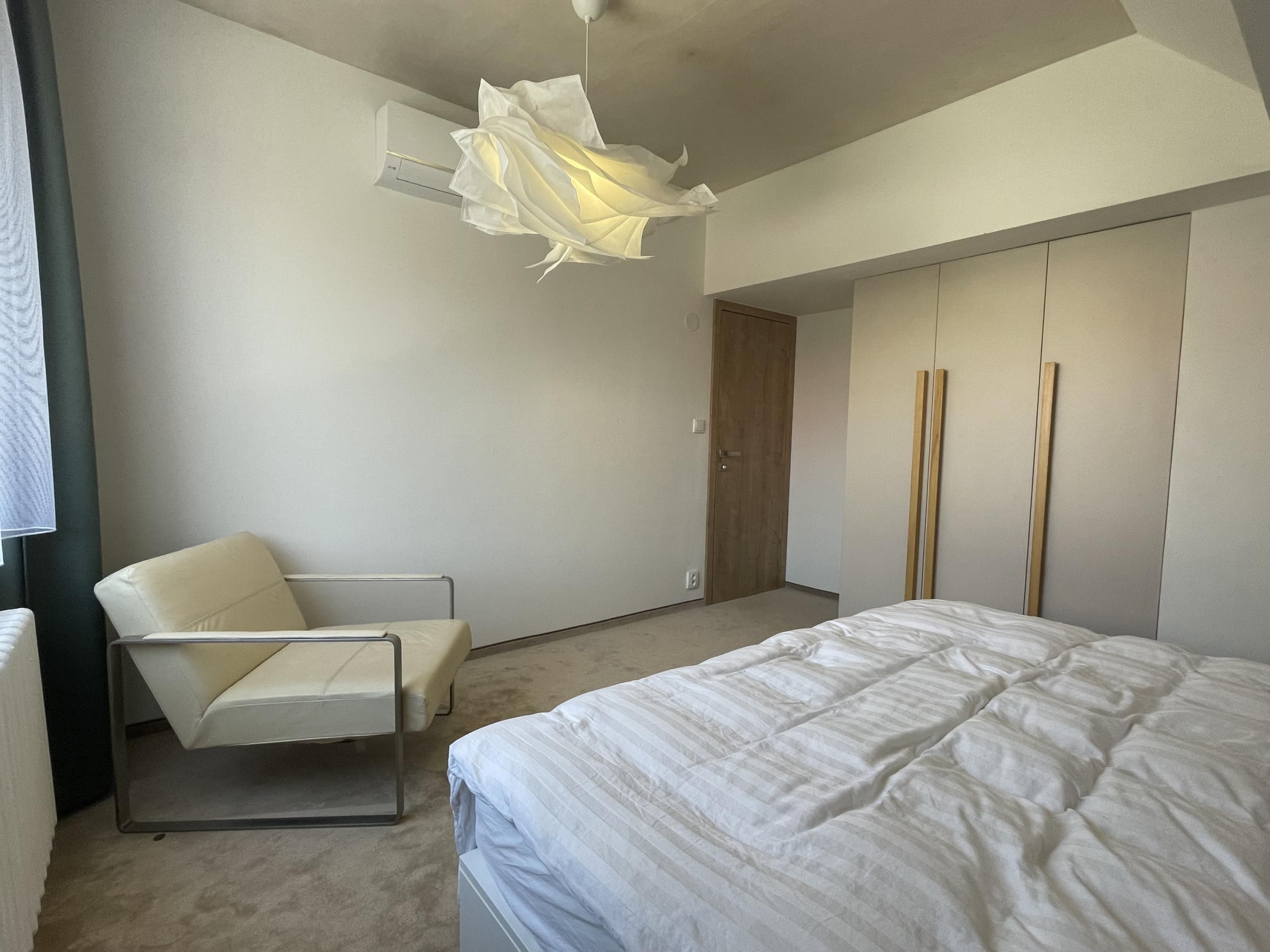 Une chambre à coucher moderne avec un lit, une chaise et une armoire.