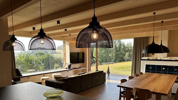 Una cocina moderna con una isla grande, una mesa de comedor de madera y lámparas colgantes.