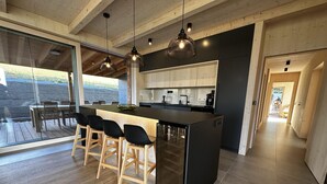 Una cocina moderna con una isla central, taburetes de madera y lámparas colgantes.