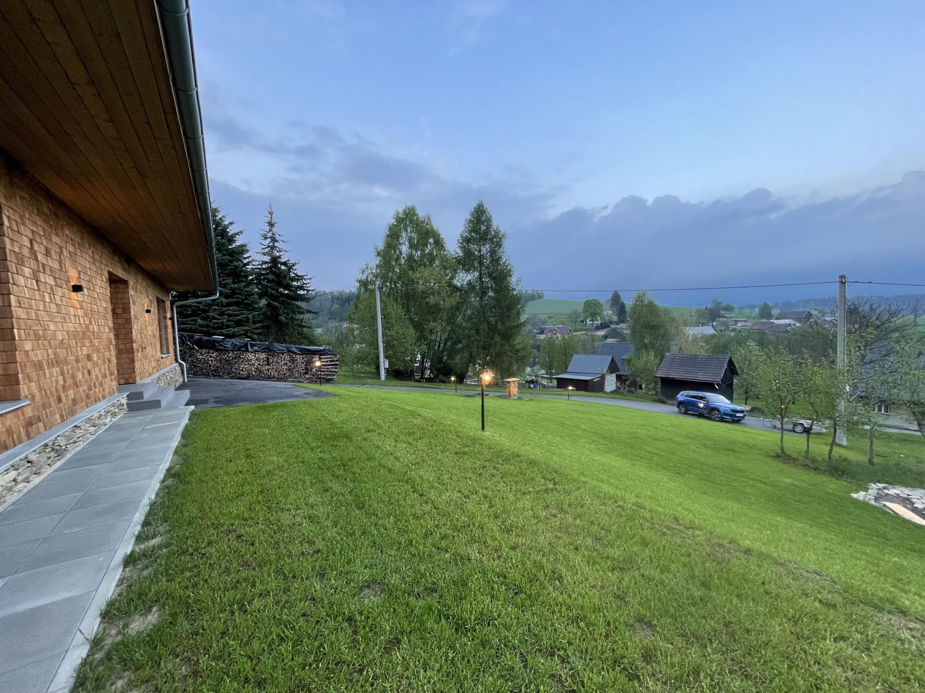 Ein Rasen mit einem Backsteingebäude, Bäumen und einer entfernten Aussicht auf Häuser und Berge.