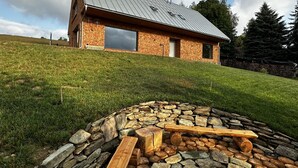Una casa moderna con techo inclinado, ventanas amplias y un área con un hogar de piedra.