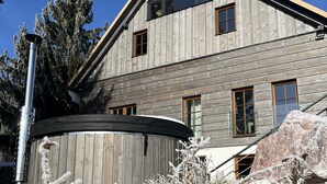 Una casa de madera de dos pisos con ventanas grandes y una chimenea visible.