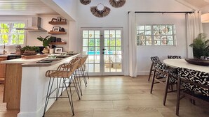 A spacious kitchen with a central island, bar stools, and a dining area with patterned chairs. - WOW STYLISH! Next2Bahamar: Pickleball, PrvPool, HotTub + Beachlife & Restaurants (Nassau)