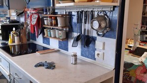 Una cocina con microondas, estufa y diferentes utensilios en estantes.