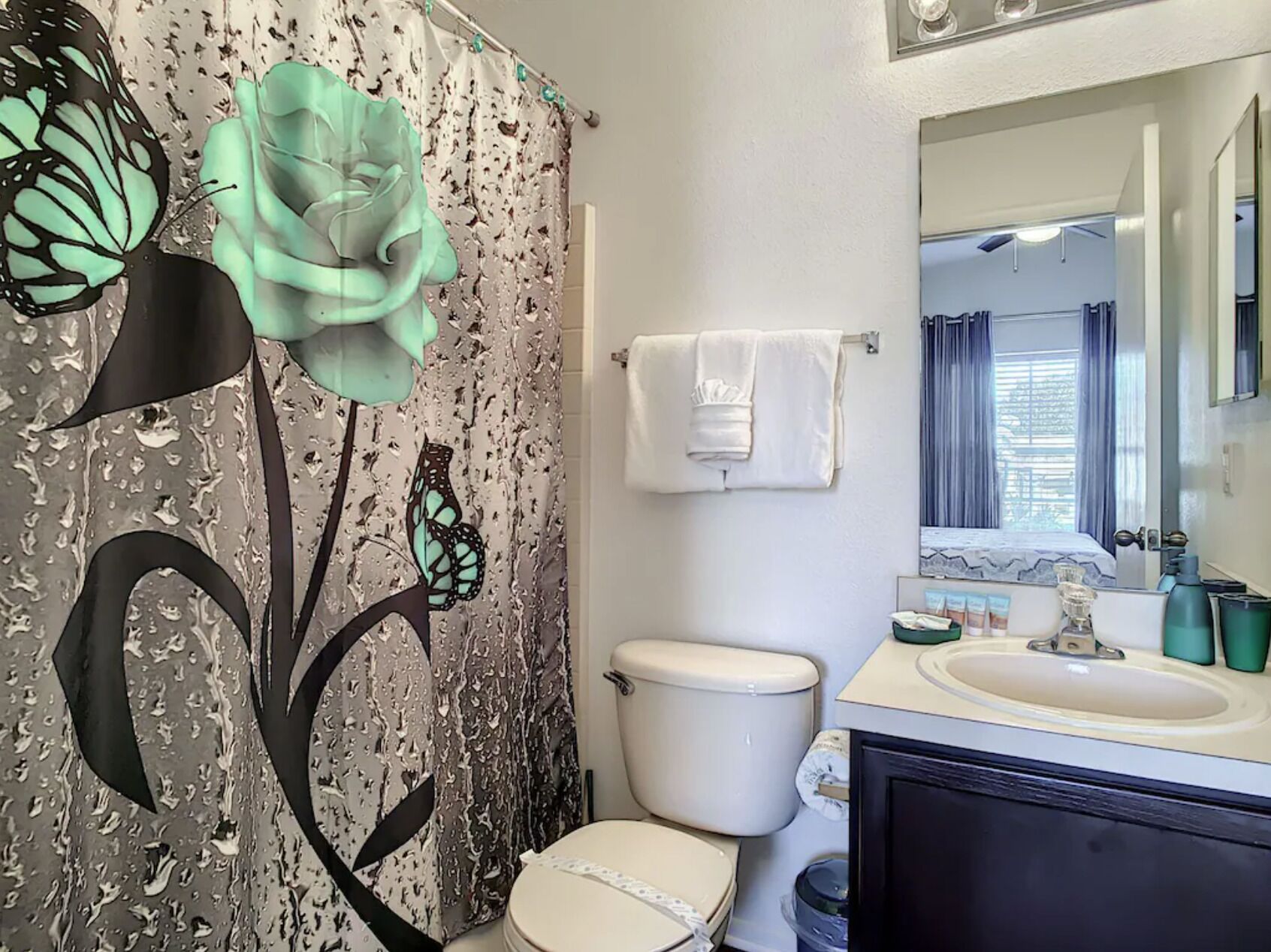 A bathroom with a toilet, sink, and a large mirror above the sink.