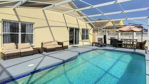 A swimming pool with a clear blue water, surrounded by a covered patio area with outdoor furniture and a pergola structure. - A Dark Siders dream in Vader's Vacation Villa.  (Davenport)