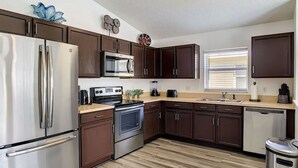 A modern kitchen with stainless steel appliances, dark wood cabinets, and a wooden floor. - A Dark Siders dream in Vader's Vacation Villa.  (Davenport)