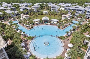 A resort with a central swimming pool surrounded by palm trees and guest rooms.