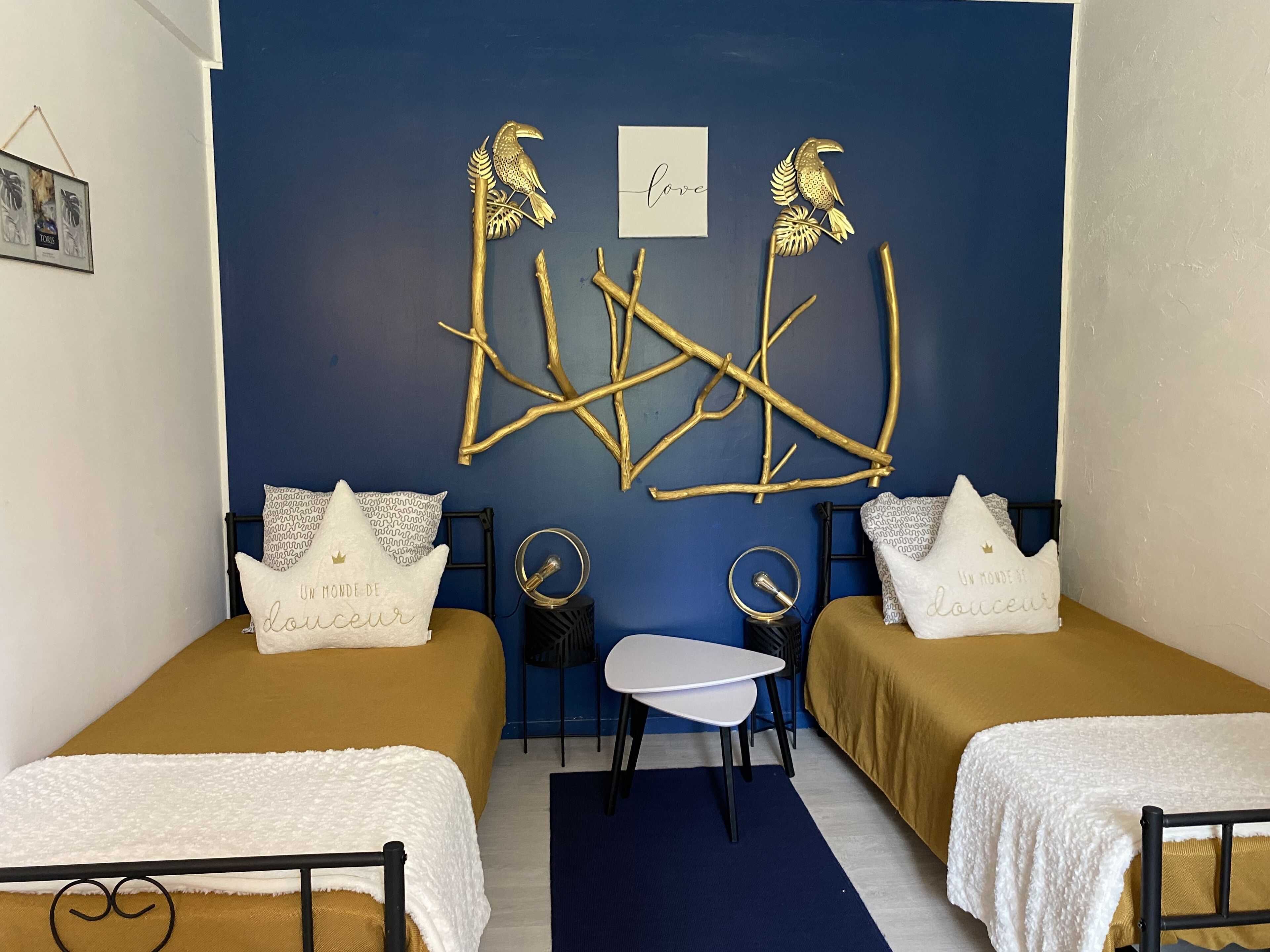 A room with two beds, a small table, and decorative wall art.