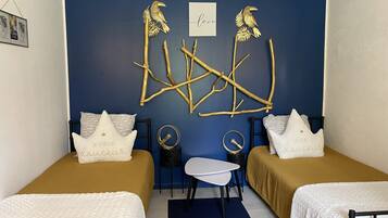 A room with two beds, a small table, and decorative wall art.