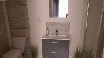 A bathroom with a toilet, a sink, and two potted plants.