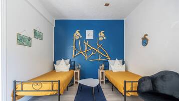 A room with two beds, a small table, and a chair.