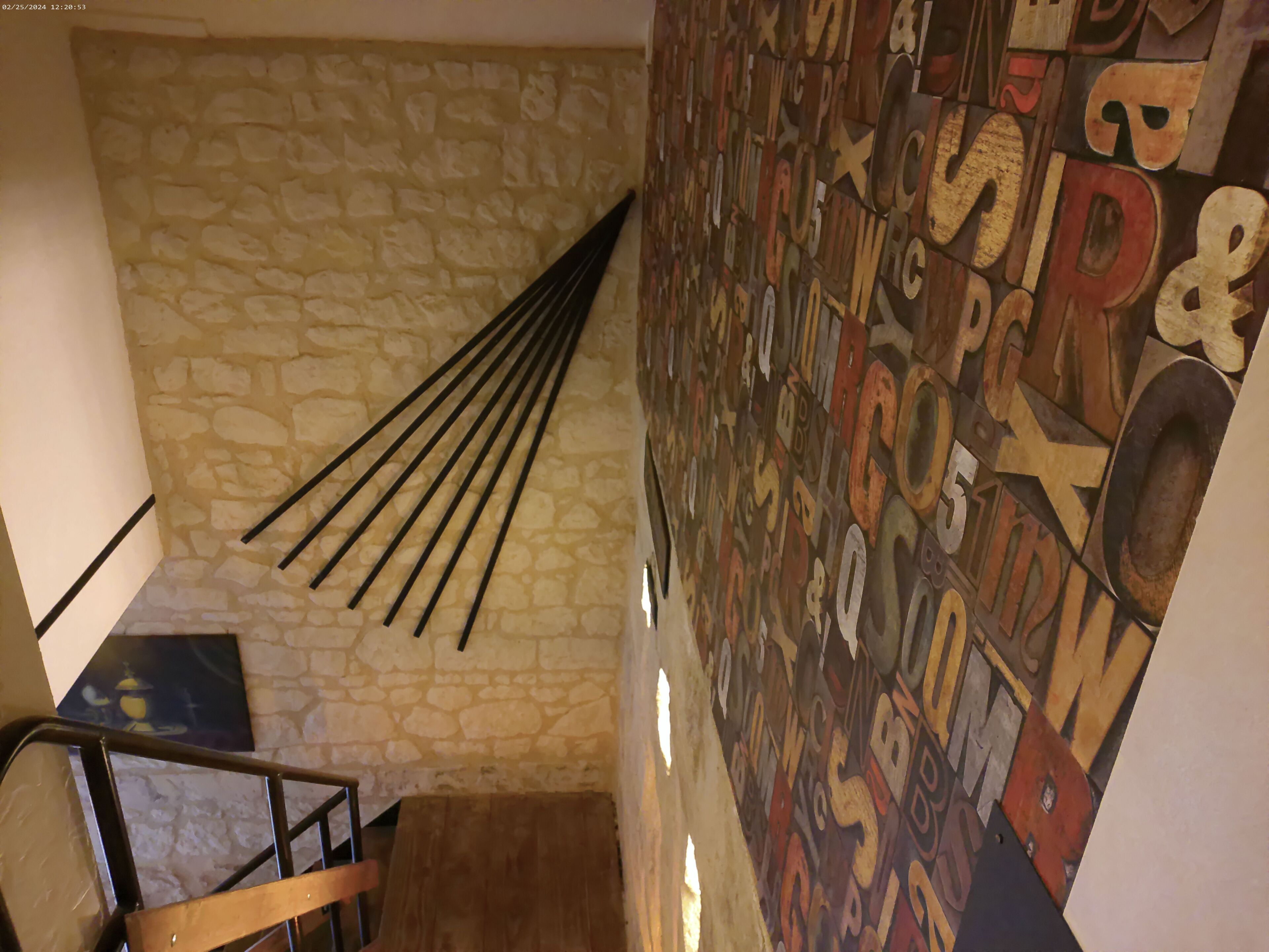 A staircase with a stone wall and a wall with various letters and symbols.