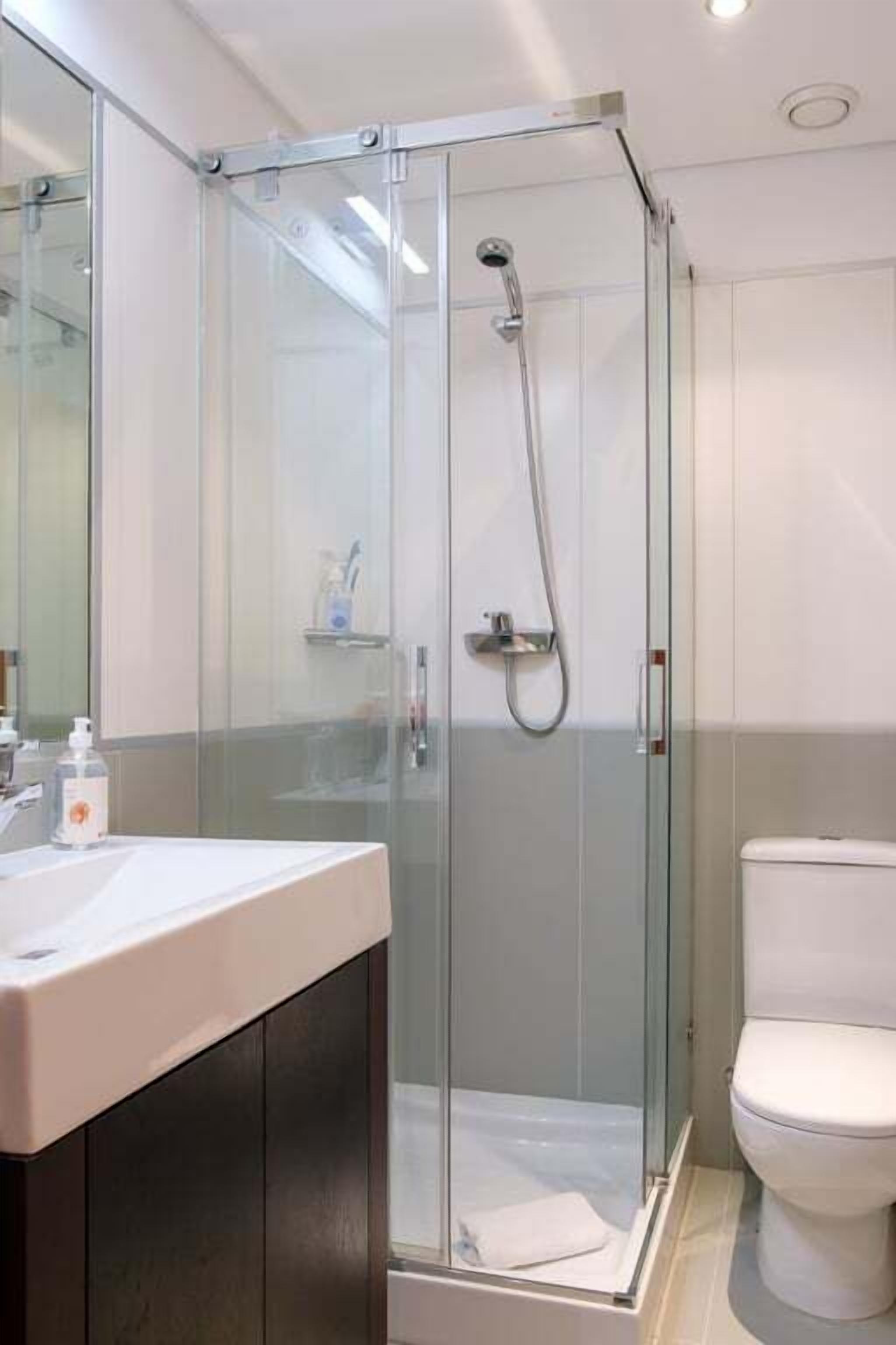 Une salle de bain moderne avec une douche à parois de verre, un lavabo blanc et des toilettes.