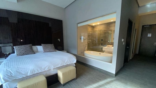 A modern bedroom with a large bed, a built-in bathtub, and a separate shower area.