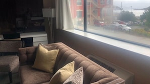 A living room with a large window, a sofa, a chair, and a lamp.