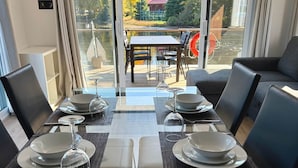 A dining area with a table set for four, overlooking a scenic view of trees and a building.