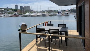 A wooden deck with tables and chairs overlooking a marina with boats.