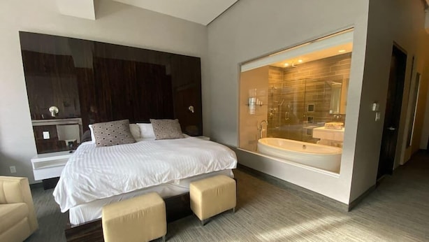 Une chambre moderne avec un grand lit, une douche en verre et un petit coin salon.