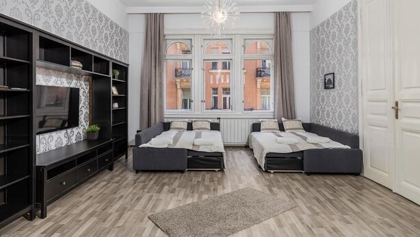 Een moderne woonkamer met twee banken, een televisie en een groot raam met uitzicht op gebouwen.