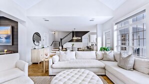 Un salon moderne avec un canapé d’angle, un pouf rond et un coin repas comprenant une table et des chaises.