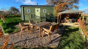 A rustic cabin with a wooden deck, a barbecue area, and a covered seating space.
