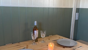 A wooden dining table with two plates, two wine glasses, a candle, and a bottle of wine.