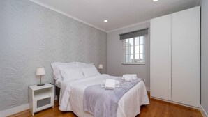 Ein ordentlich eingerichtetes Schlafzimmer mit Bett, Nachttischen, einem Fenster und einem Kleiderschrank.