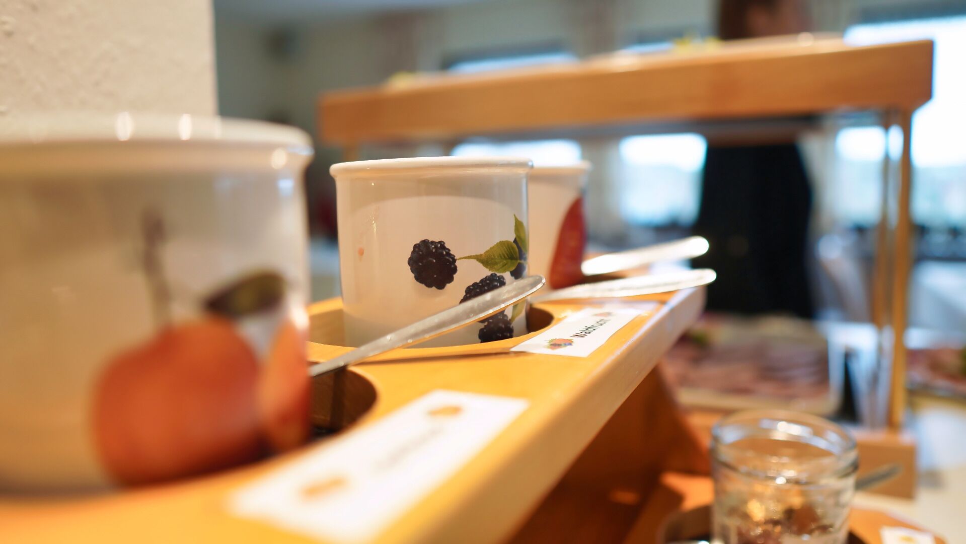 A coffee station with a cup of coffee and a spoon on a tray.