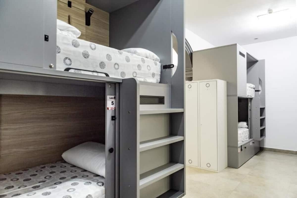 Habitación con literas, un armario y una pequeña estantería.