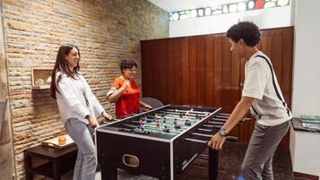 Una habitación con mesa de fútbol, pared de ladrillo y paneles de madera.