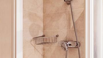 A shower with a handheld showerhead and a wall-mounted faucet, a towel rack, and a shower control panel.