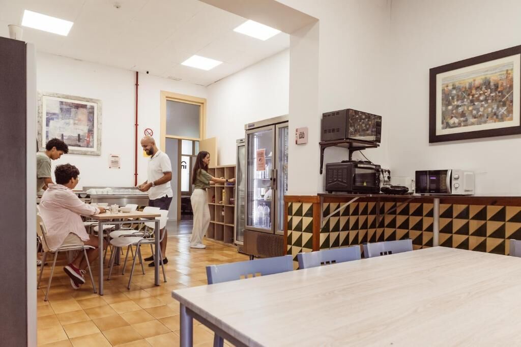 A dining area with tables and chairs, a refrigerator, a microwave, and a coffee machine.