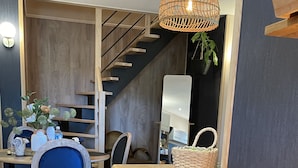 Un comedor moderno con una mesa de madera, sillas negras y una cesta de mimbre.