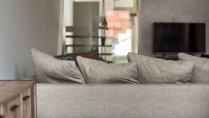 A modern living room with a sofa, a television, and a dining area in the background. - Historical Two-Bedroom Penthouse in the Centre - Kolkovna (Hlavní mesto Praha)