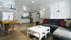 Ein modernes Wohnzimmer mit einer Couch, einem Esstisch und einer Küche im Hintergrund.