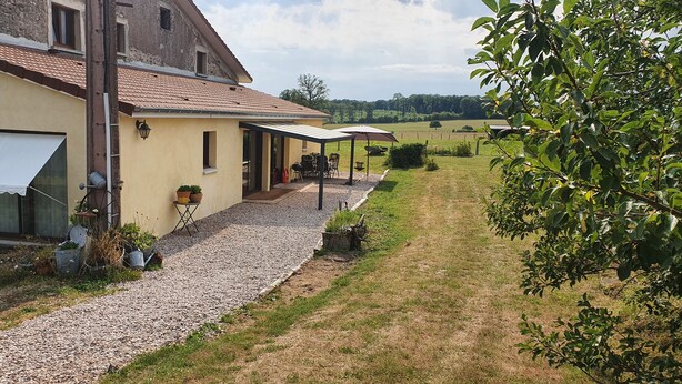 A rustic building with a gravel driveway, outdoor seating, and a garden area.