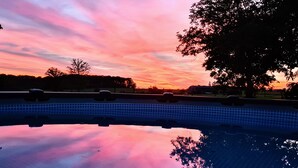 A swimming pool with a tiled edge and a clear reflection of the sky and trees.