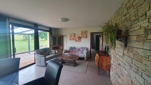 A spacious living room with a large window, a sofa, a coffee table, and a stone wall.