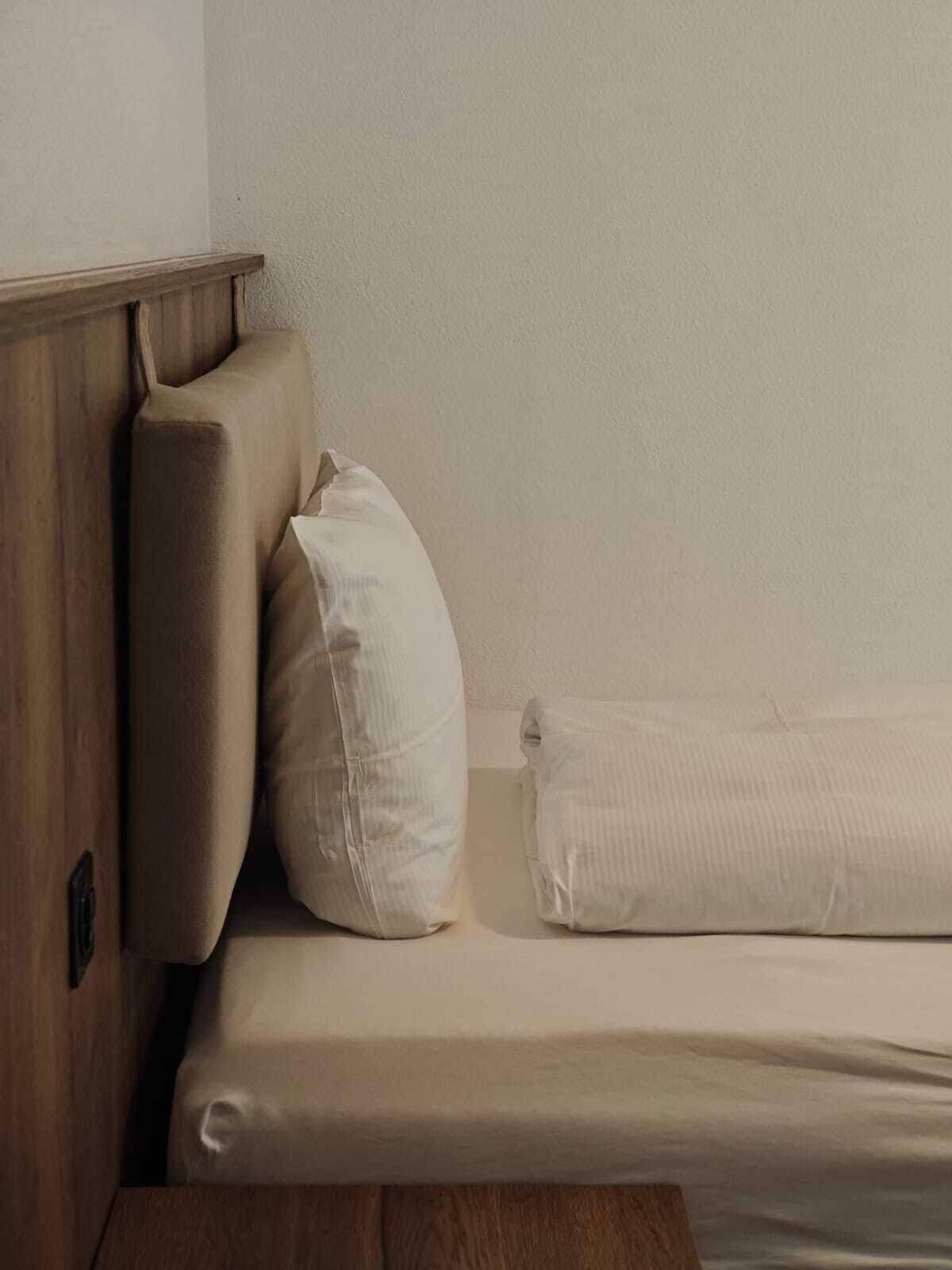 A bed with a wooden headboard and two pillows.