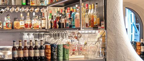 A bar area with multiple shelves of liquor bottles and glasses, two chairs, and a round table.