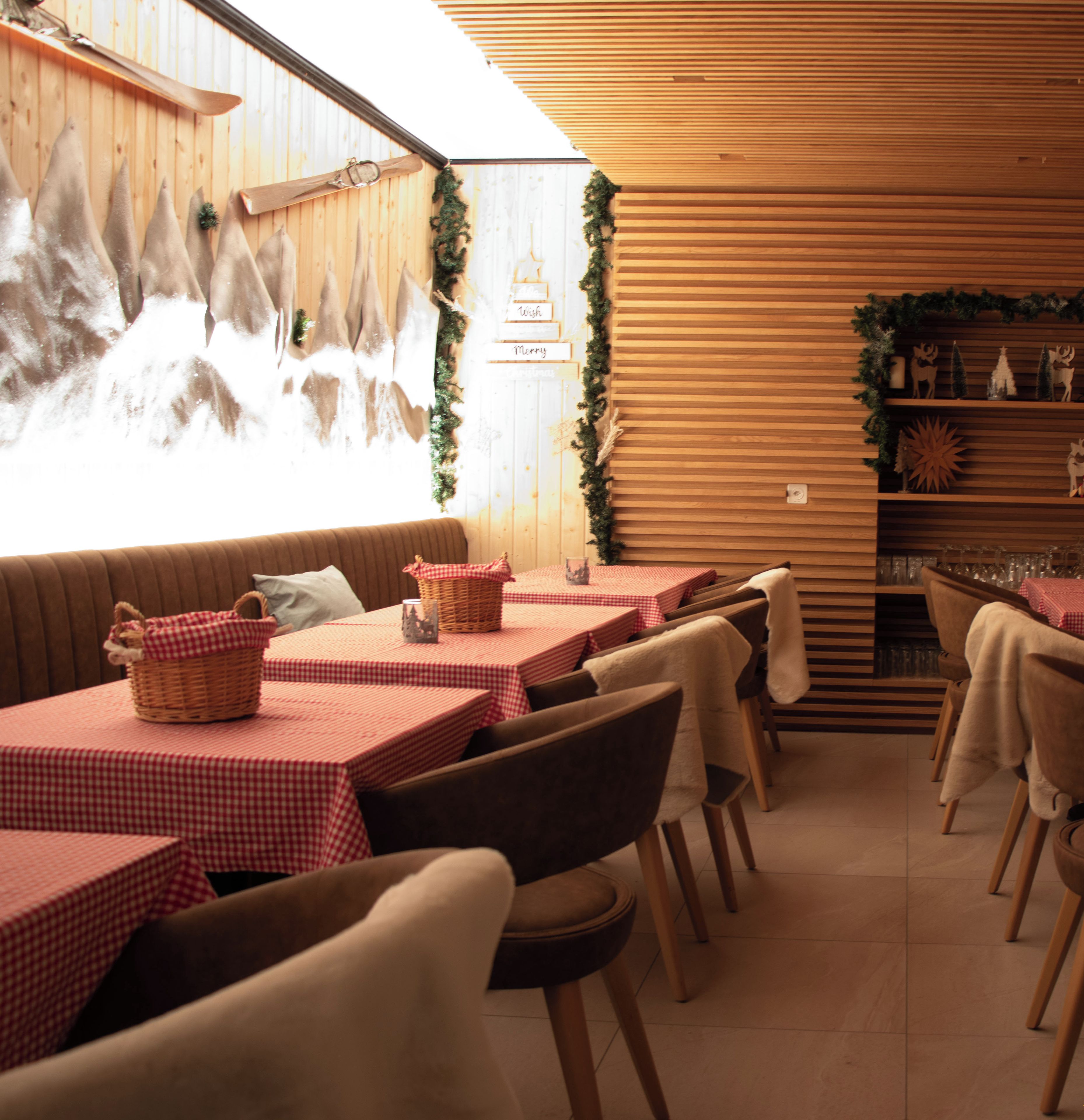 En mysig restaurang med träpanel på väggarna, rödrutiga bord och bruna stolar.