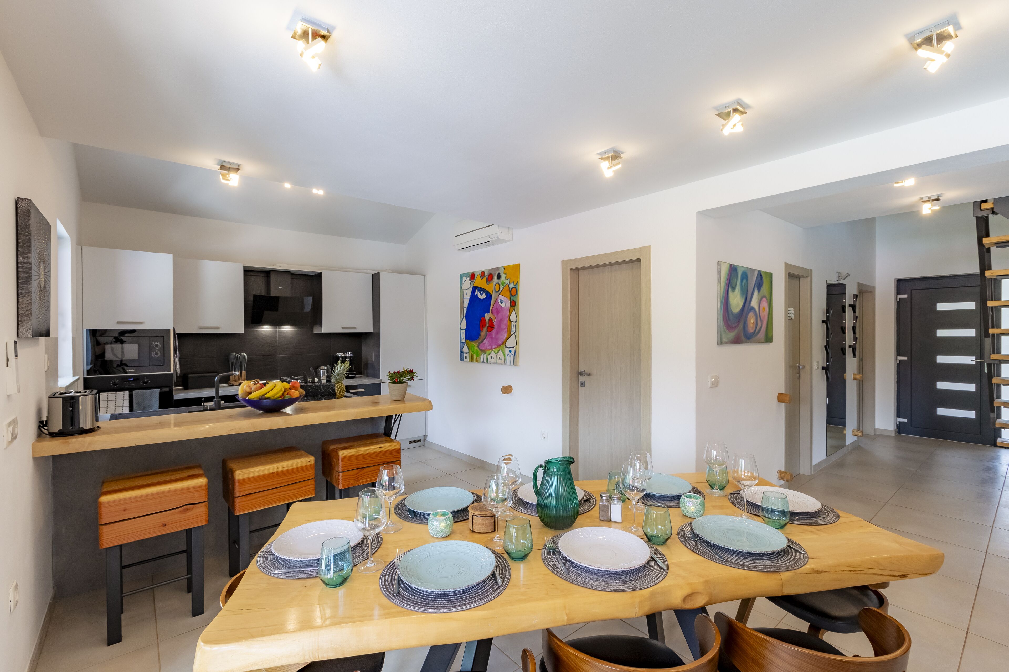 A modern kitchen with white cabinets, a central island, and a dining area with a wooden table set for six.