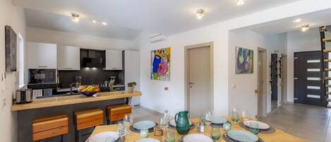 A modern kitchen with white cabinets, a central island, and a dining area with a wooden table set for six.
