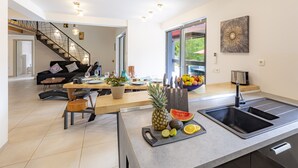 A modern kitchen with a central island, a built-in sink, and a dining area with a sofa and table.