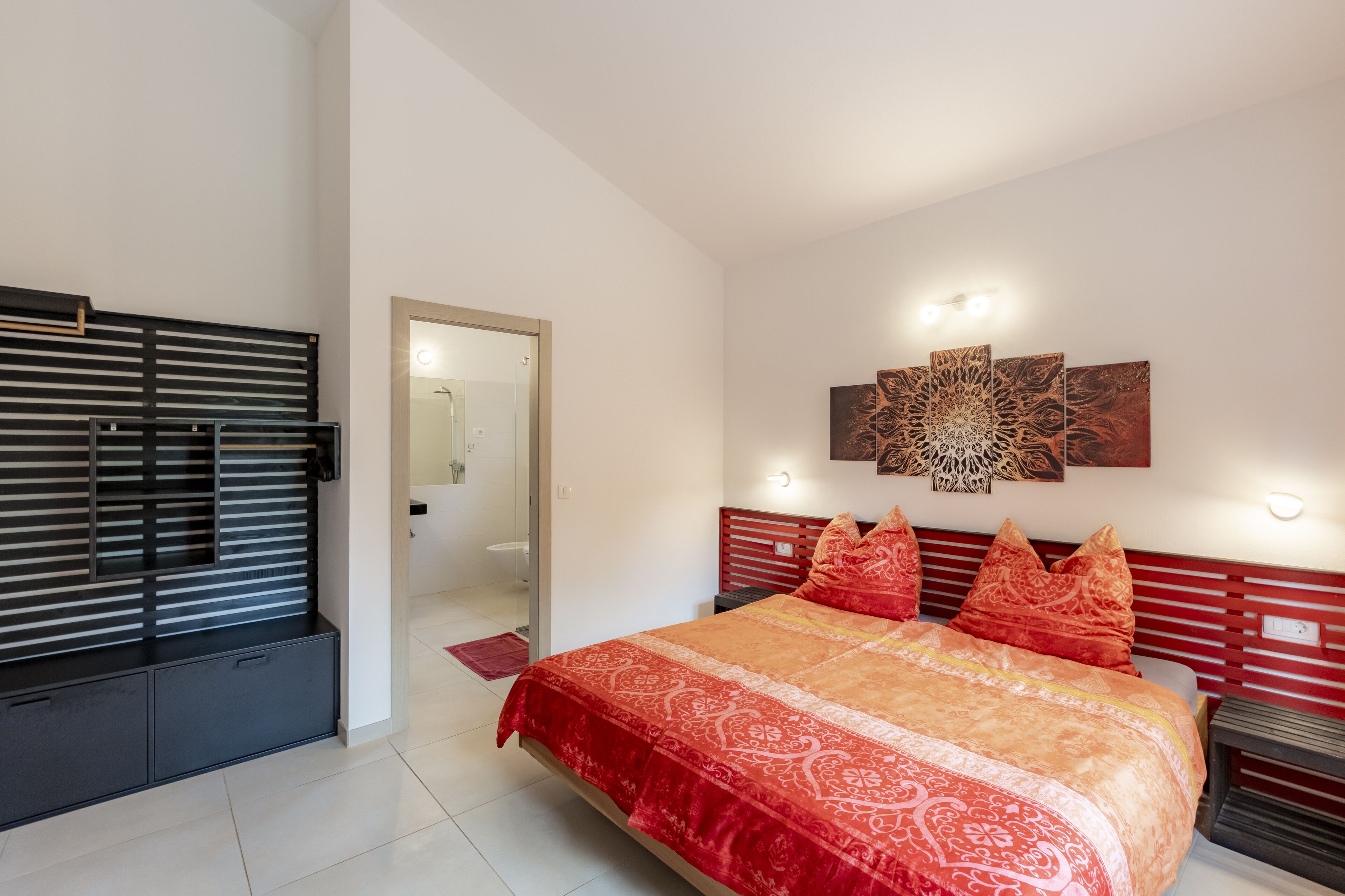 A modern bedroom with a large bed, a wooden headboard, and a decorative wall piece.