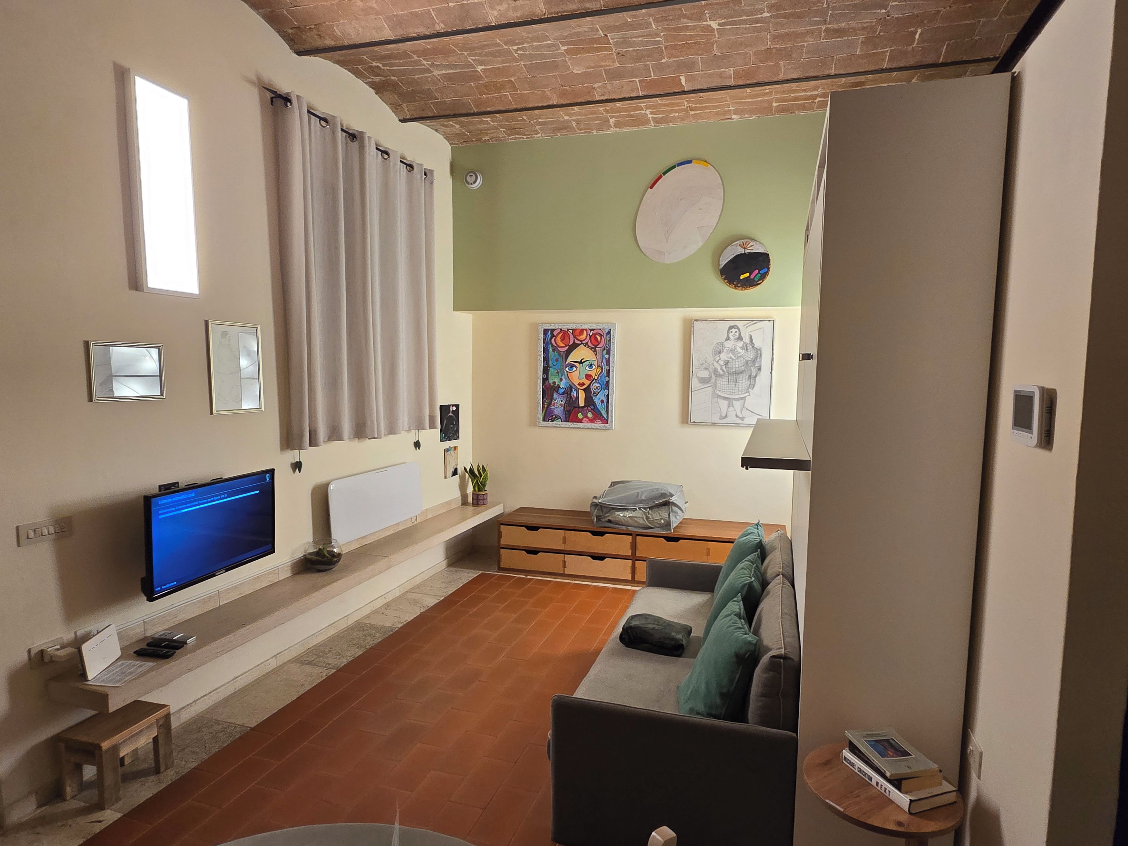 A living room with a television, a sofa, a coffee table, and artwork on the walls.
