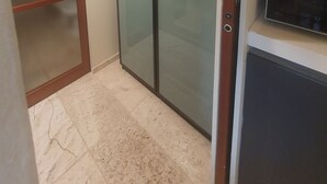 Habitación con puerta corrediza de vidrio, microondas integrado y piso de baldosas.