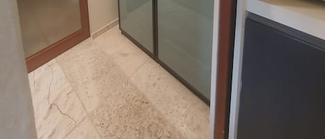 A room with a sliding glass door closet, a built-in microwave, and a tiled floor.