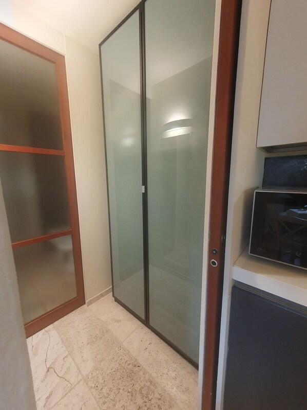 Habitación con puerta corrediza de vidrio, microondas integrado y piso de baldosas.